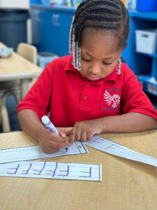 Child in red shirt practicing writing.