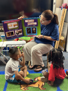 Teacher reading a book to two students